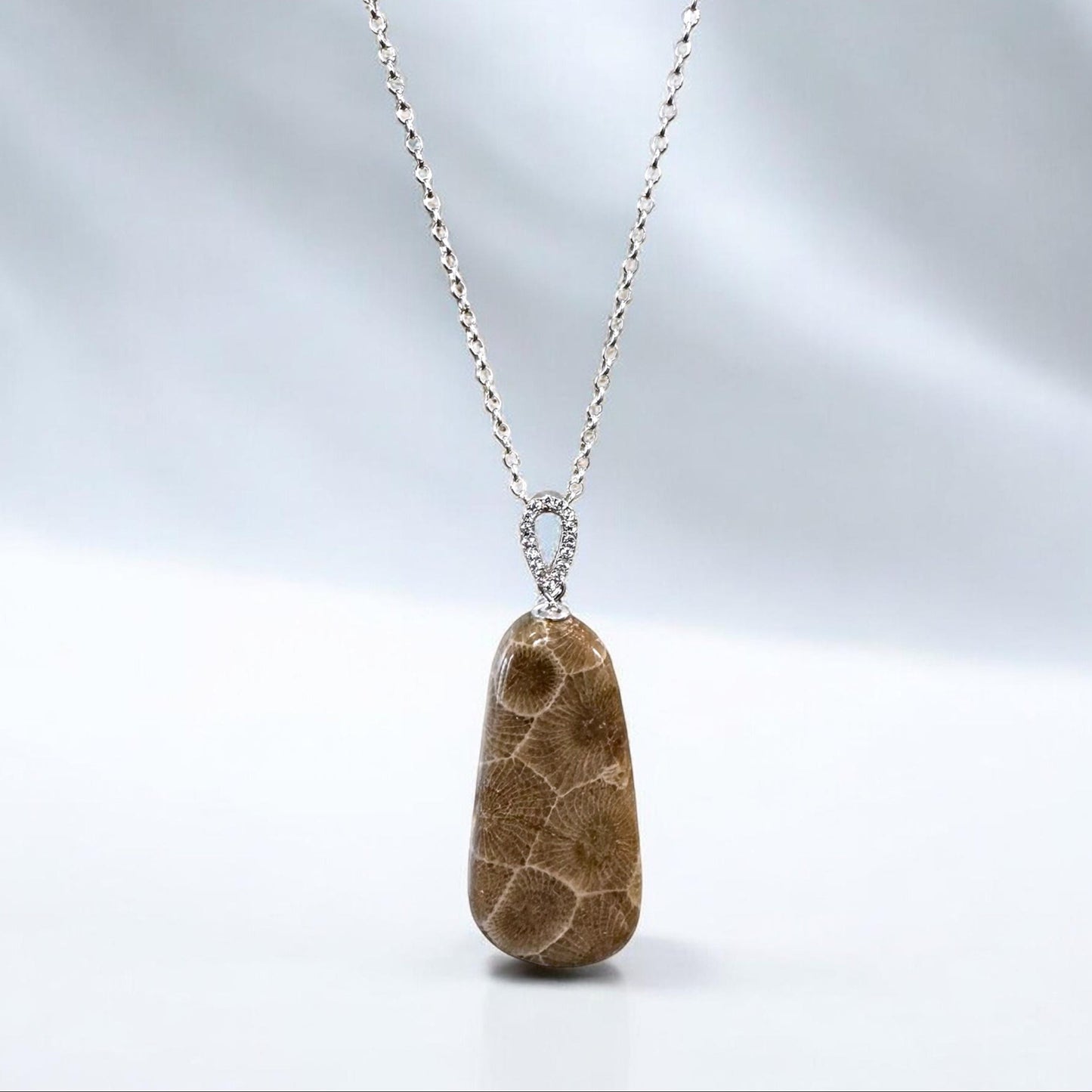 Petoskey stone pendant hanging on a sterling silver cable chain with white background