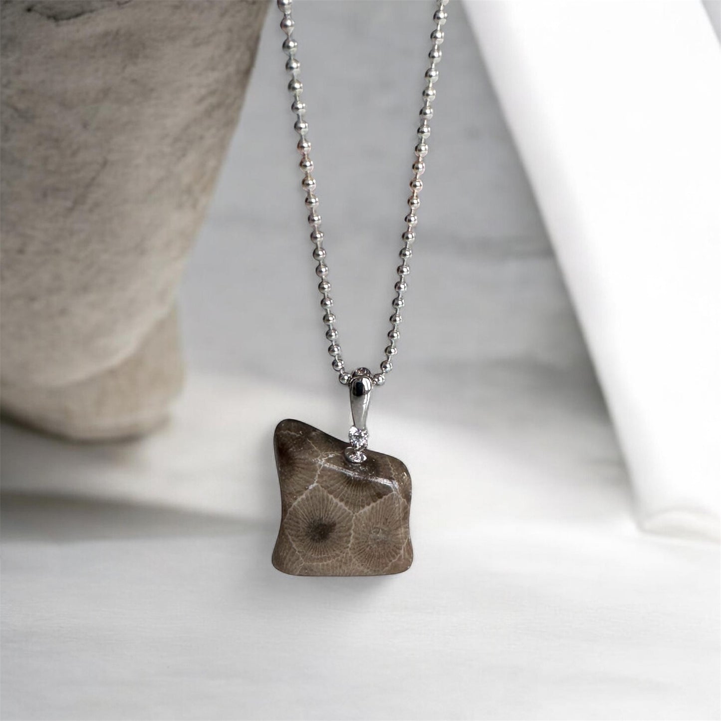 Necklace with a bear shaped petoskey stone pendant on a neutral background