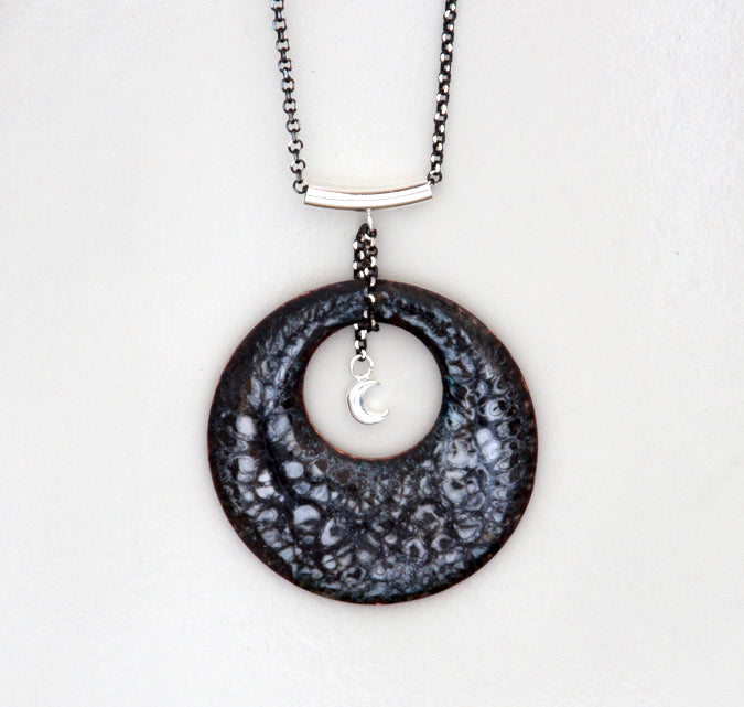 Round black gray and white enamel pendant necklace with quarter moon hanging in the center. Hung from a silver bail and chain.