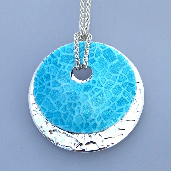 Lake Bed enamel pendant necklace has two circle embossed discs, one colored turquoise, one sterling silver.