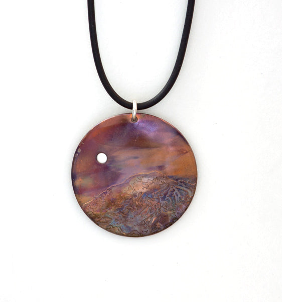 Serenity is a flame painted copper pendant necklace with etched mountain and fine silver moon in the sky