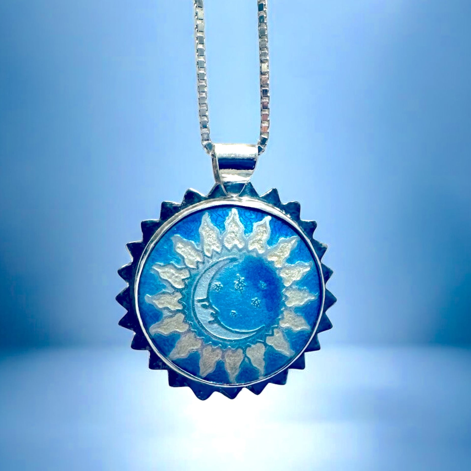 Moon and sun blue and silver pendant necklace on a blue background 