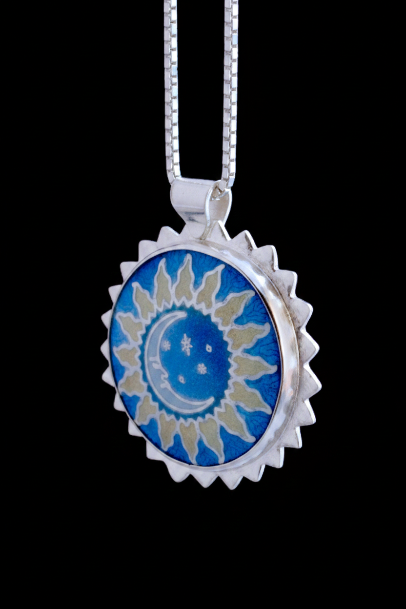 Silver pendant with a white moon, stars, and golden sun rays on a blue background 