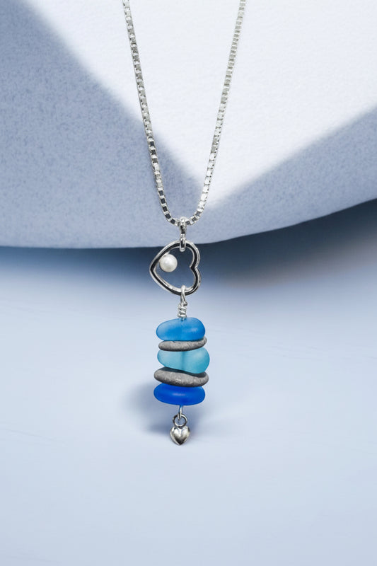 Beach lovers heart pendant necklace with beach stones and blue glass on a light blue background