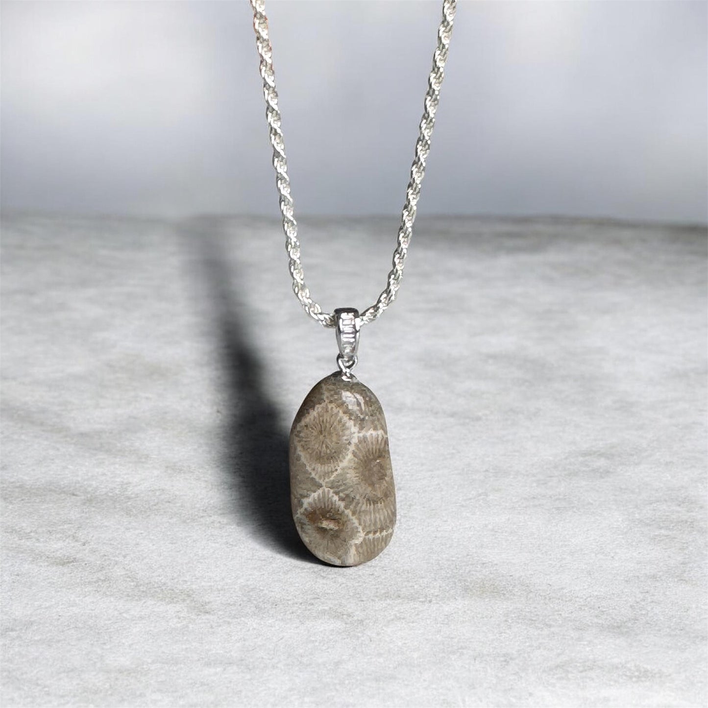 Necklace with a Petoskey stone pendant on a light gray background