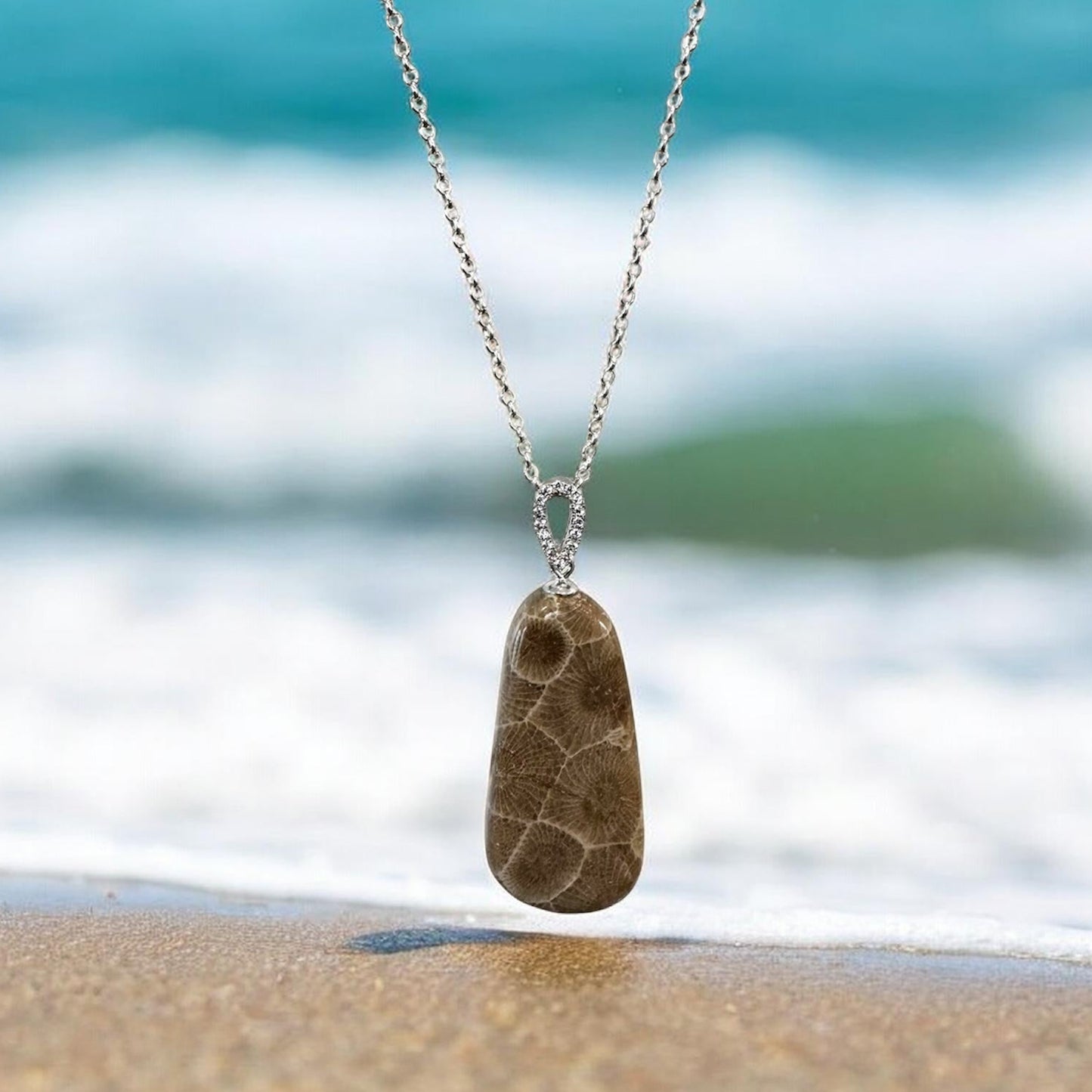 Necklace with a Petoskey stone pendant on a beach with Lake Michigan waves in the background