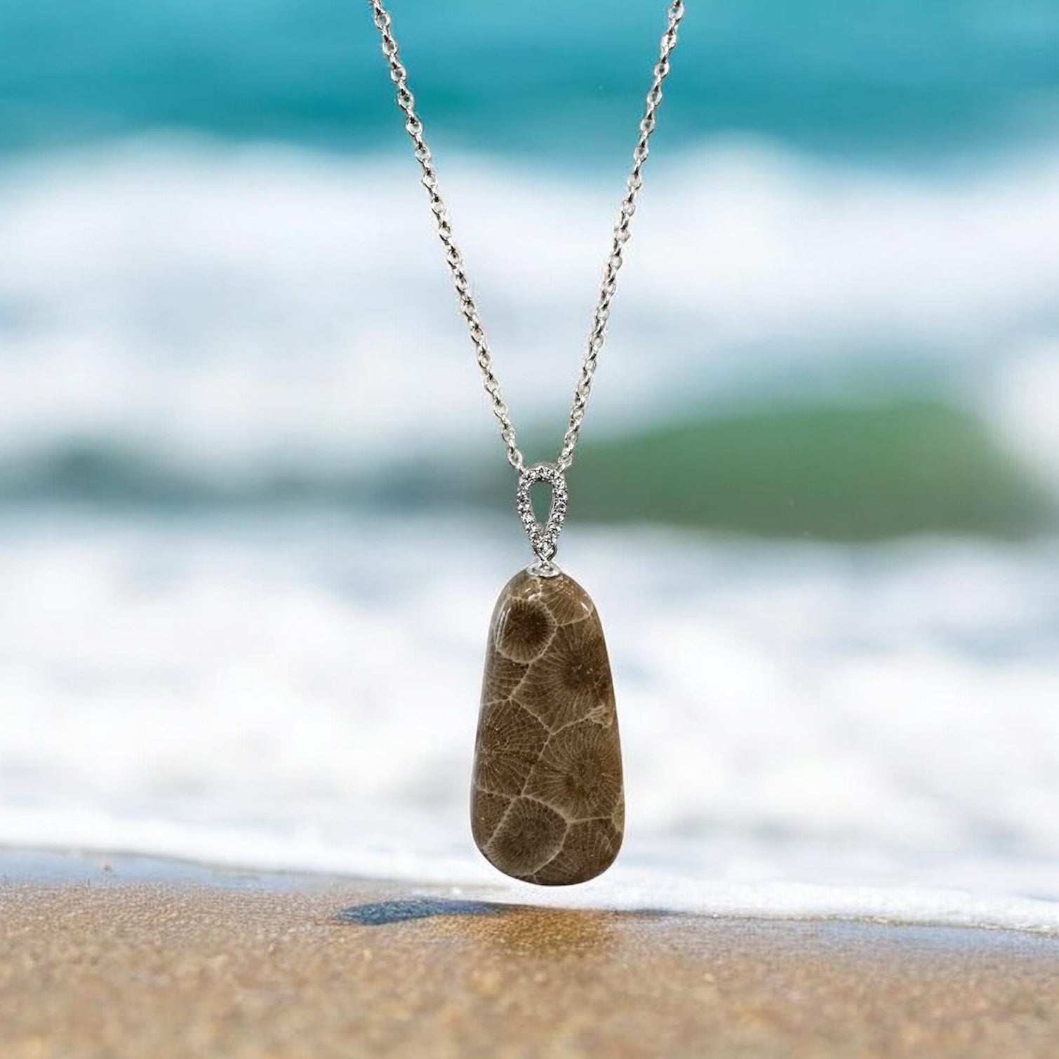 Necklace with a Petoskey stone pendant on a beach with Lake Michigan waves in the background