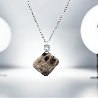 Necklace with a square pendant featuring a petoskey stone on a blurred background