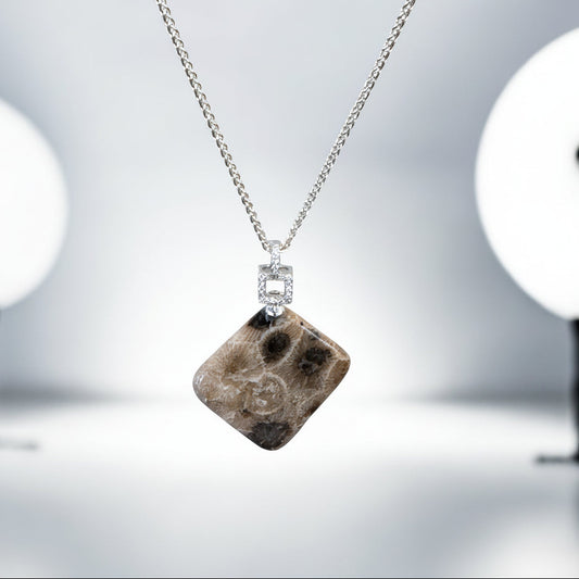 Necklace with a square pendant featuring a petoskey stone on a blurred background