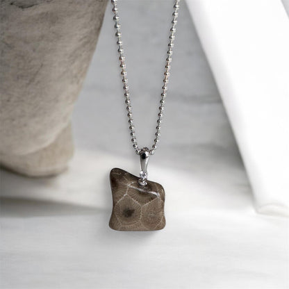 Necklace with a bear shaped petoskey stone pendant on a neutral background