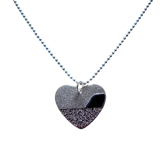 Heart-shaped sand dune and beach scene pendant on a silver chain against a white background