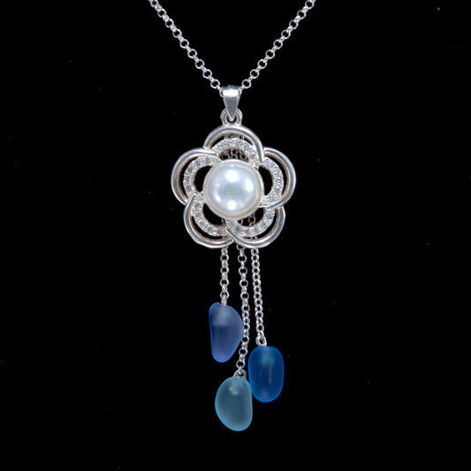 Silver flower pendant with cubic zirconia and white pearl. Blue, teal and purple beach glass hang on silver dangle chains