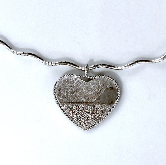Silver Heart shaped pendant necklace with embossed image of sand dunes, lake and sky. Hangs on sterling silver chain